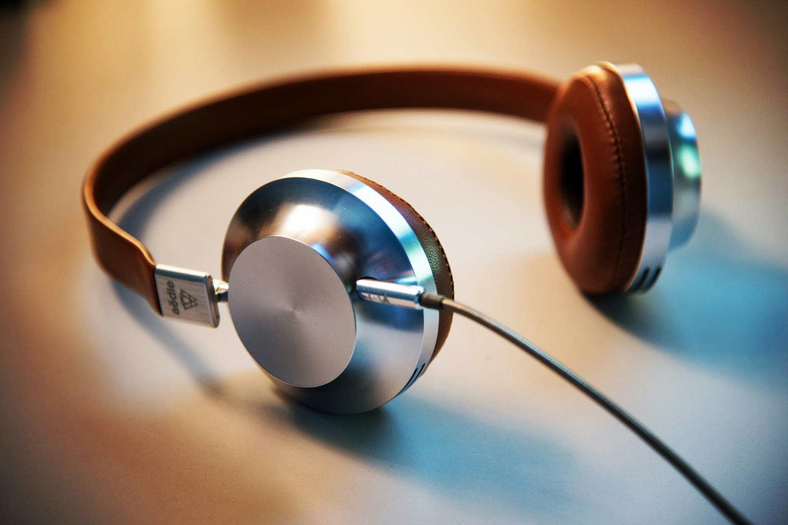 Brown leather on-ear headphones with silver cups and a cable.